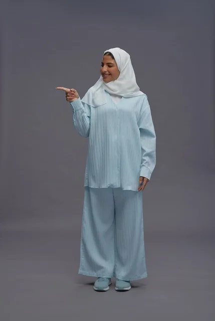 امرأة سعودية بالحجاب تشير لمساحة إعلانية في استوديو