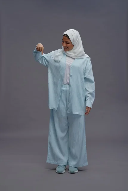 امرأة سعودية تشير للأسفل بزي محتشم في الاستوديو