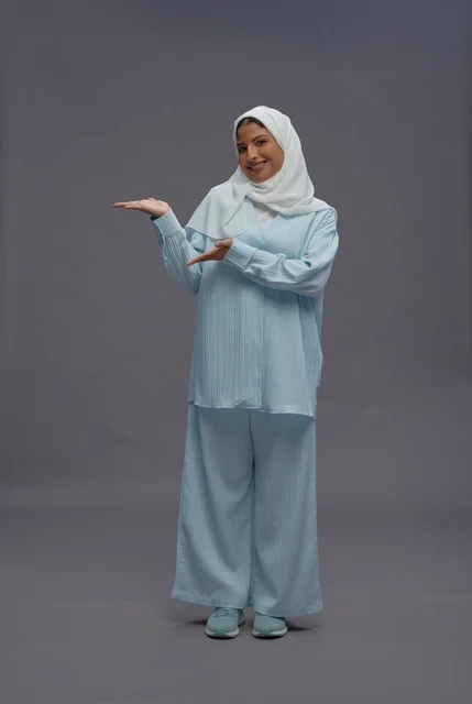 امرأة سعودية بالحجاب تقدم منتجاً على خلفية رمادية