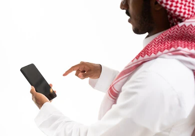 رجل سعودي يستخدم الهاتف الذكي على خلفية بيضاء