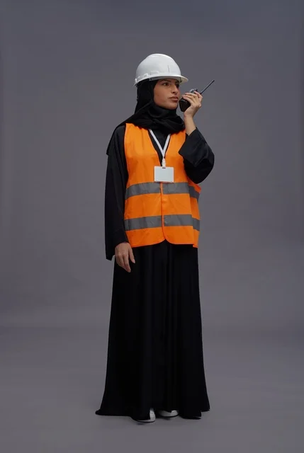 مهندسة سعودية ترتدي سترة السلامة وتمسك بجهاز لاسلكي