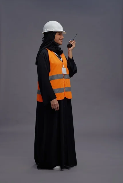 مهندسة سعودية ترتدي سترة السلامة وتحمل جهاز لاسلكي