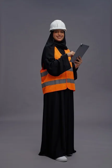 مهندسة سعودية ترتدي سترة السلامة وتستخدم جهازاً لوحياً