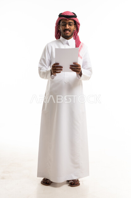 رجل سعودي بالزي التقليدي يقرأ وثيقة ورقية