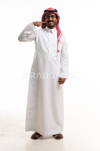 رجل سعودي بالثوب التقليدي يشير إلى ابتسامته