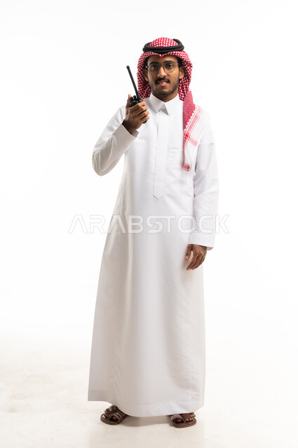 رجل سعودي بالثوب يحمل جهاز لاسلكي بخلفية بيضاء