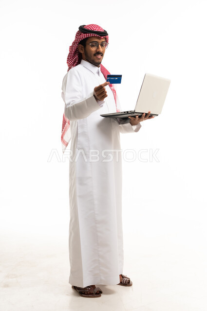 رجل سعودي يستخدم اللابتوب وبطاقة الائتمان بخلفية بيضاء