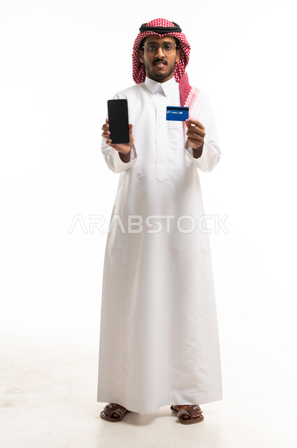 رجل سعودي يحمل هاتف ذكي وبطاقة ائتمان في الاستوديو
