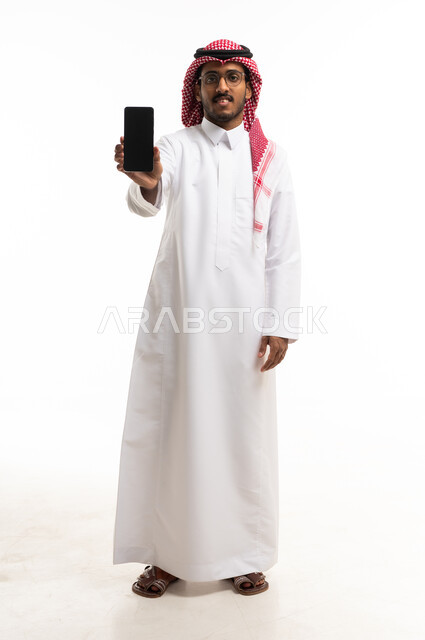 رجل سعودي يحمل هاتفاً ذكياً بشاشة فارغة