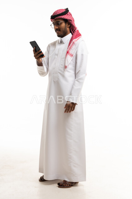 Saudi Man in Traditional Thobe Using Smartphone