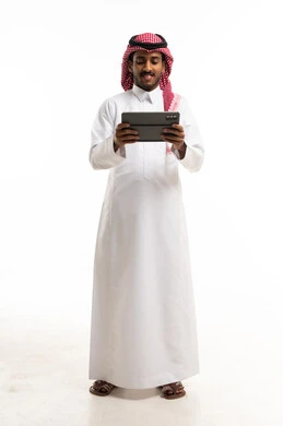رجل سعودي بالثوب التقليدي يستخدم جهاز لوحي رقمي