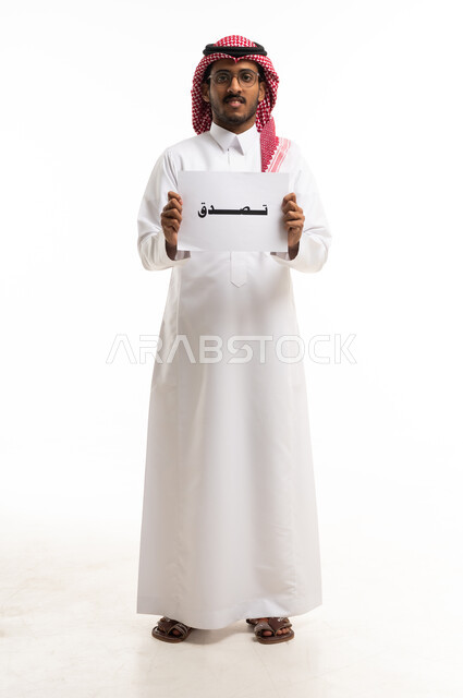 رجل سعودي يحمل لوحة تصدق على خلفية بيضاء