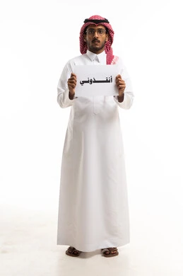 رجل سعودي يحمل لوحة مكتوب عليها أنقذوني