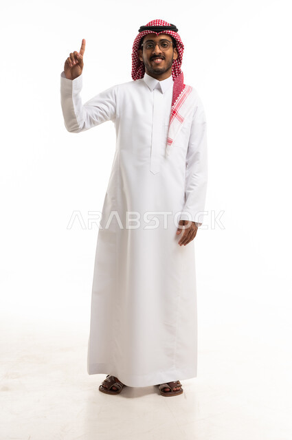 رجل سعودي بالزي التقليدي يشير بإصبعه للأعلى