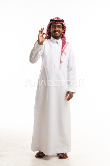 رجل سعودي بالثوب التقليدي يشير بعلامة الموافقة