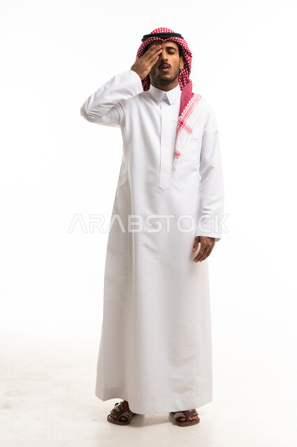 رجل سعودي بالثوب التقليدي يغطي عينه على خلفية بيضاء