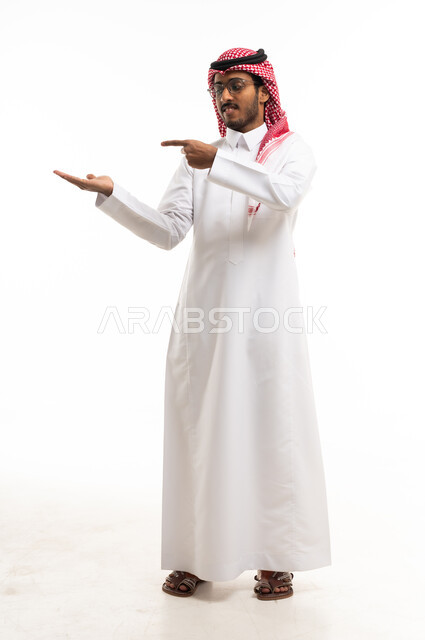 رجل سعودي بالزي التقليدي يشير بيده على خلفية بيضاء