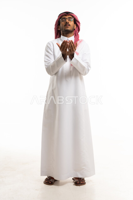 رجل سعودي يصلي بالثوب التقليدي على خلفية بيضاء