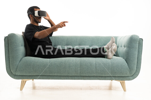 رجل عربي يستخدم نظارة الواقع الافتراضي على الأريكة