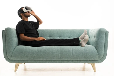 رجل عربي يستخدم نظارة واقع افتراضي على أريكة