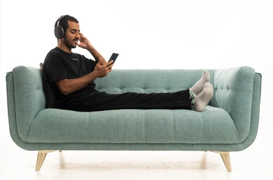 شاب سعودي مع سماعات يسترخي على أريكة في الاستوديو