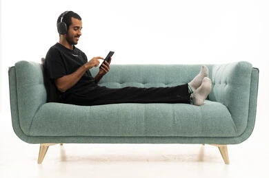 شاب عربي يستخدم هاتفاً ذكياً على أريكة حديثة