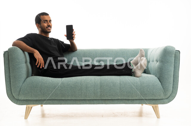 Saudi Man Relaxing on Sofa with Smartphone