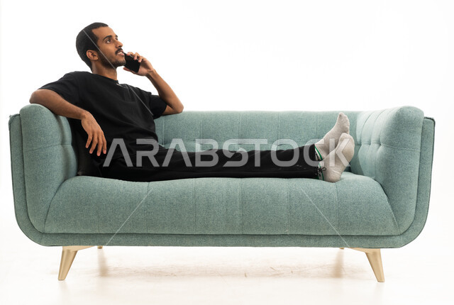 رجل عربي يسترخي على أريكة خضراء يتحدث بالهاتف