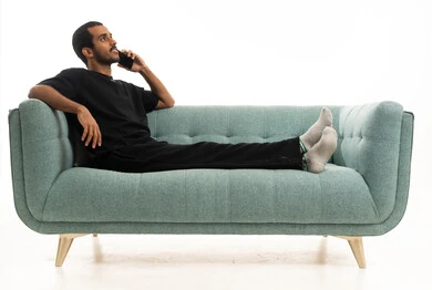 رجل عربي يسترخي على أريكة خضراء يتحدث بالهاتف