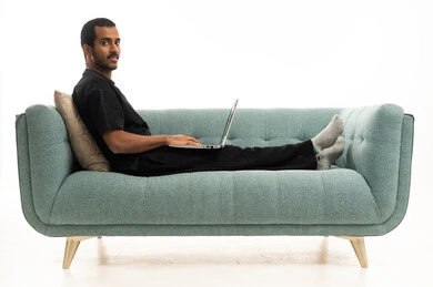 Saudi Man Using Laptop on Modern Sofa White Background