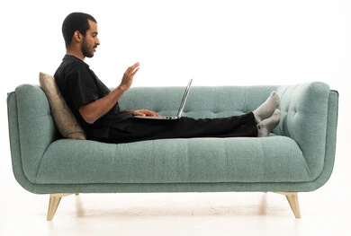 شاب عربي بزي طبي يستخدم اللابتوب على الأريكة