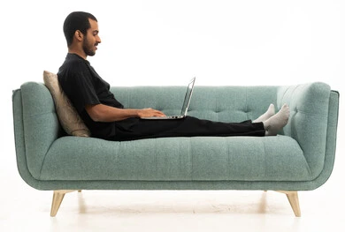 رجل سعودي يستخدم اللابتوب على أريكة خضراء حديثة