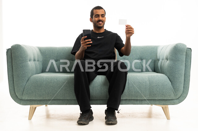 رجل سعودي يستخدم الهاتف الذكي وبطاقة الائتمان