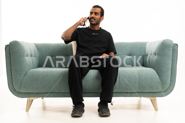 Saudi Man on Green Sofa Talking on Smartphone