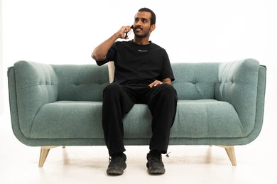 Saudi Man on Green Sofa Talking on Smartphone