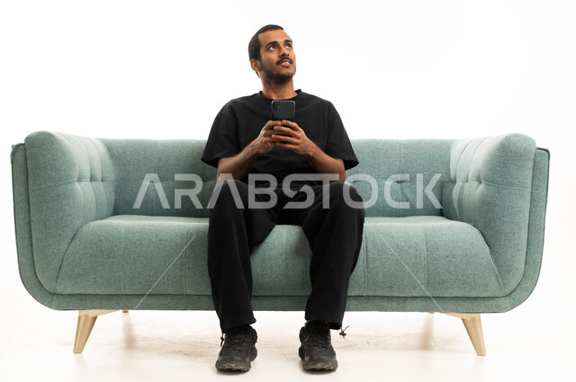 Saudi Man Sitting on Sofa with Smartphone