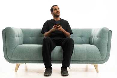 Saudi Man Sitting on Sofa with Smartphone
