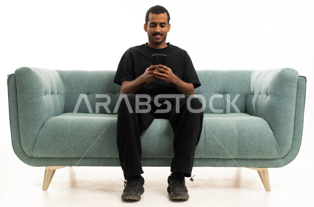 Saudi Man on Sofa Using Smartphone Studio Shot
