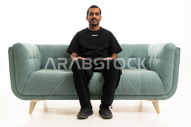 رجل سعودي يجلس على أريكة خضراء حديثة في استوديو