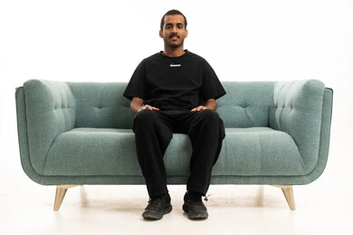 رجل سعودي يجلس على أريكة خضراء حديثة في استوديو