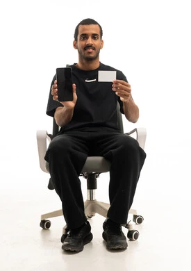 رجل سعودي يحمل هاتفا وبطاقة بيضاء في الاستوديو