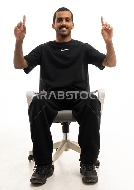 شاب سعودي يشير للأعلى على كرسي مكتب خلفية بيضاء