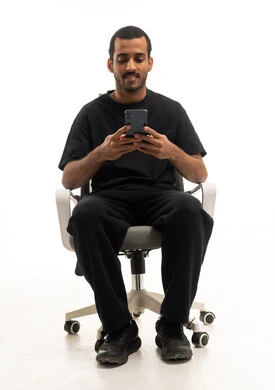 شاب عربي يستخدم الهاتف الذكي على كرسي مكتب