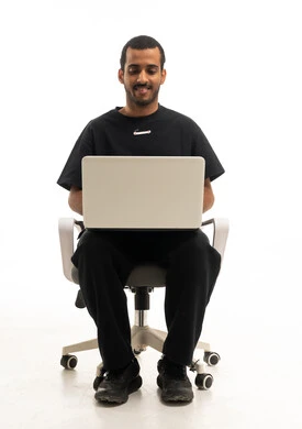 شاب سعودي يستخدم لابتوب على خلفية بيضاء