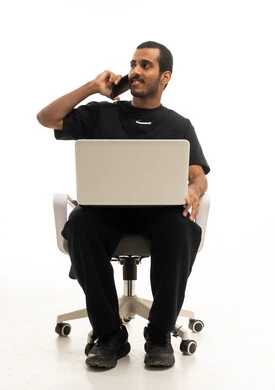 رجل سعودي مع كمبيوتر محمول وهاتف بخلفية بيضاء