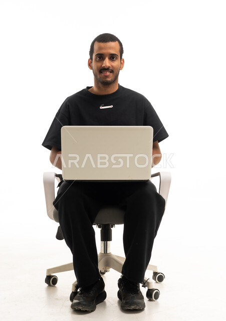 رجل سعودي يستخدم اللابتوب على كرسي مكتب في استوديو