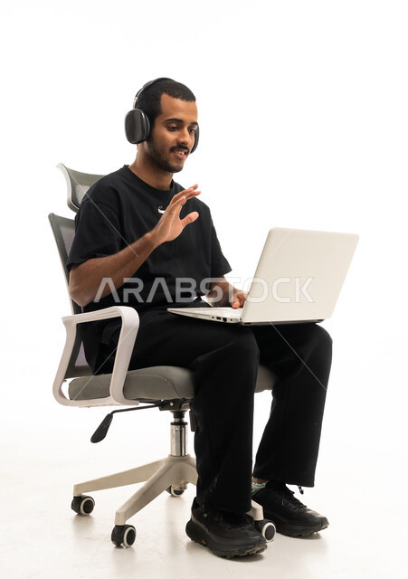 رجل سعودي يستخدم اللابتوب والسماعات في مكالمة فيديو