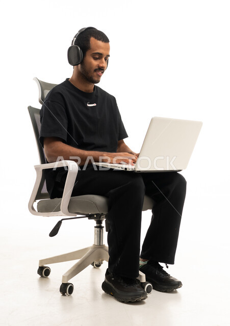 رجل يعمل على لاب توب مع سماعات بخلفية بيضاء