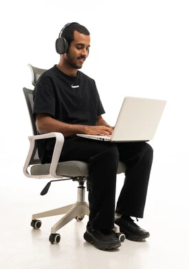 رجل يعمل على لاب توب مع سماعات بخلفية بيضاء