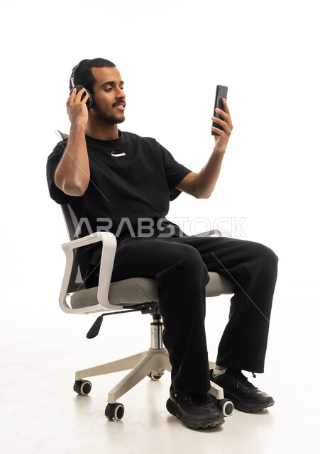 Saudi Man with Headphones on Office Chair with Smartphone